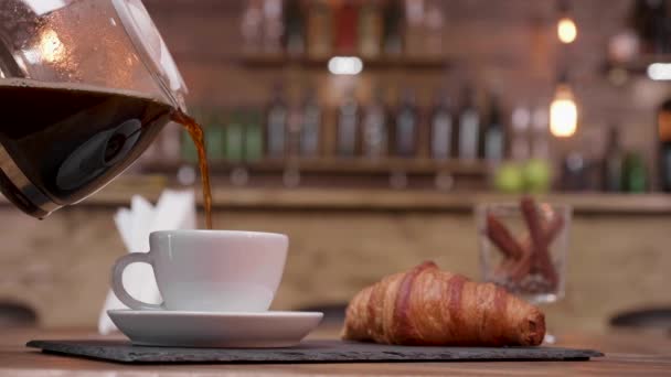 Cinematógrafo de una cafetera llenando una taza en una bandeja con croissant
 - Metraje, vídeo