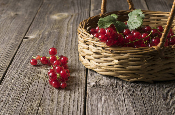 fresh red currants in basket on wooden surface - 写真・画像