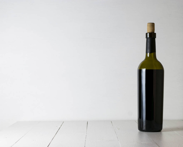 Red wine bottle and corkscrew on white wooden table background with copy space - Photo, Image