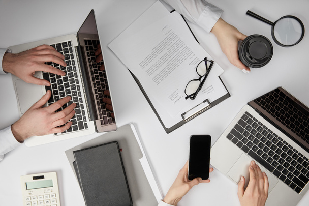 vista superior de empresários digitando em laptops, segurando smartphone e copo de papel
 - Foto, Imagem