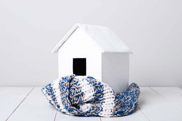 house in winter - heating system concept and cold snowy weather with model of a house wearing a knitted cap - Zdjęcie, obraz