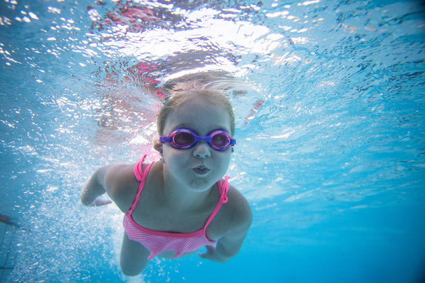 Szeroki kąt pod wodą zdjęcie dziewczyny malucha kąpieli w dużym basenie z gogle i różowe bikini - Zdjęcie, obraz