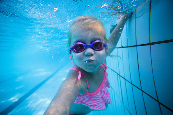 Geniş açı sualtı fotoğraf gözlük ve pembe bikini ile büyük bir yüzme havuzunda Yüzme bir yürümeye başlayan çocuk kız - Fotoğraf, Görsel