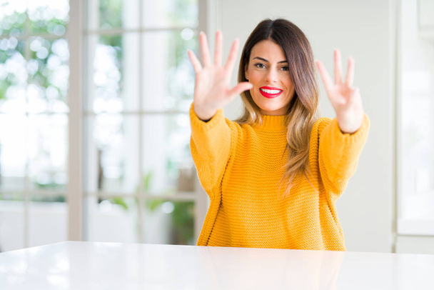 Mladá krásná žena na sobě zimní svetr doma ukazující a směřující nahoru s prsty číslo osm, zatímco s úsměvem a spokojené. - Fotografie, Obrázek