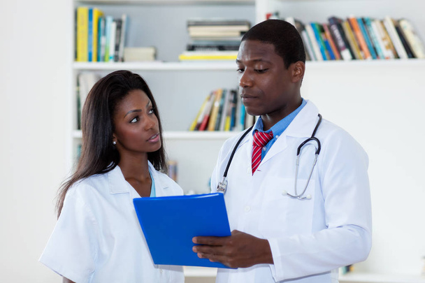 African american male doctor talking with nurse about patient - Foto, imagen