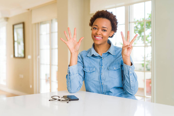 Jonge mooie Afrikaanse Amerikaanse vrouw tonen en met vingers omhoog nummer acht terwijl lacht zelfverzekerd en blij. - Foto, afbeelding