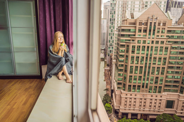 Woman wrapped in a blanket and looking at the big city - Foto, imagen