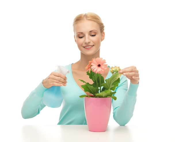 Woman holding pot with flower and spray bottle - Fotó, kép