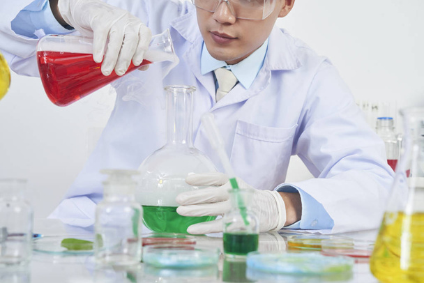 Cropped image of scientist mixing various reagents in big flask - Zdjęcie, obraz