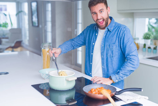 Handsome man cooking pasta at home - Fotoğraf, Görsel