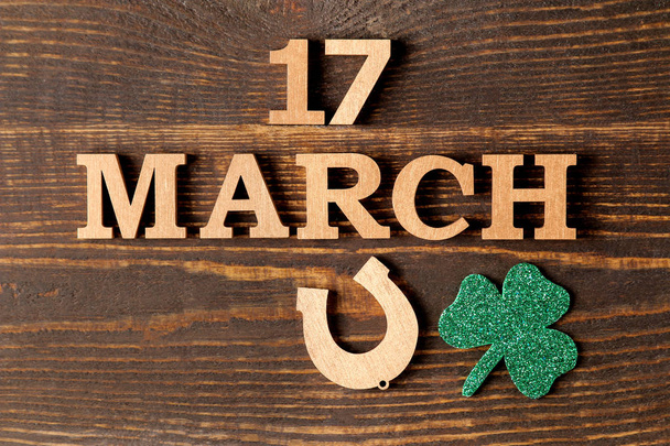 St.Patrick barátait nap. ünnepe. zöld levelei lóhere és a Patkó és a szöveg, a március 17-én a barna háttér. szemközti nézet. - Fotó, kép