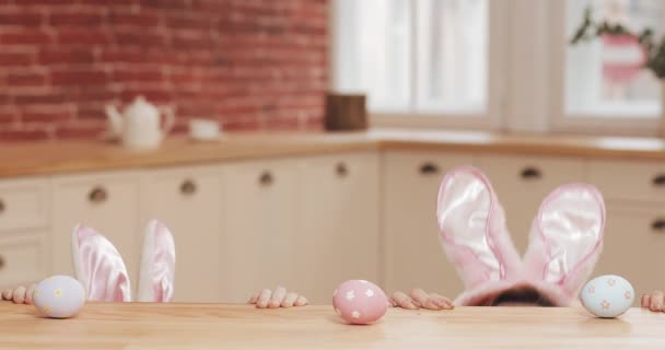 Happy easter. Young mother and daughter begin to hunt for Easter eggs wearing bunny ear. Happy family preparing for Easter in the cozy kitchen - Filmmaterial, Video