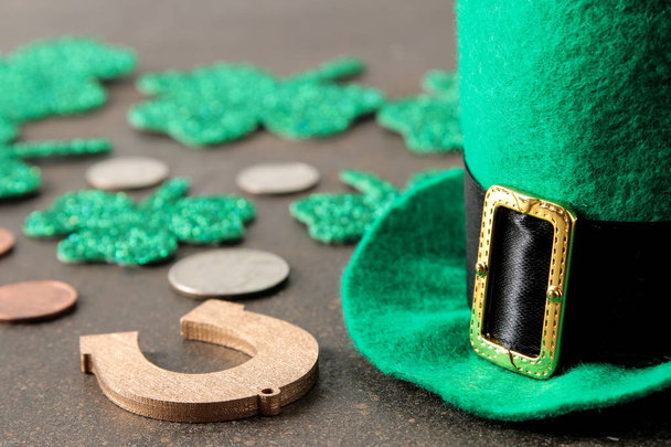 St. Patrick 's Day. Feiern. eine grüne Koboldmütze, Geld und ein Kleeblatt und ein Hufeisen auf braunem Hintergrund. - Foto, Bild