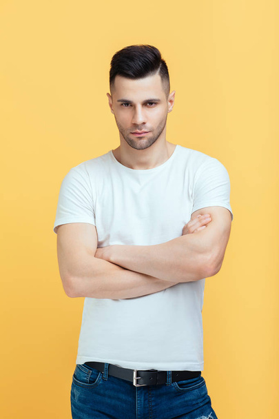 Young handsome man with crossed arms on yellow background - Photo, image