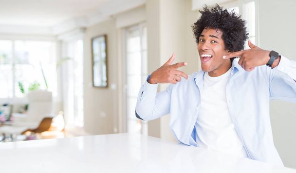 African American man at home smiling confident showing and pointing with fingers teeth and mouth. Health concept. - Photo, Image