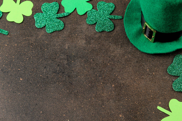St.Patrick 's Day. a holiday. Frame of green leaves of clover and leprechaun hat on a brown background. top view. space for text - Photo, Image