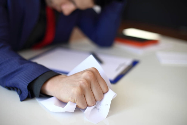 Τσαλακωμένο χαρτί στο χέρι του επιχειρηματία. Θυμωμένος και κουρασμένος άνθρωπος τσαλάκωμα έγγραφα στο γραφείο. Άγχος ή αποτυχία έννοια - Φωτογραφία, εικόνα