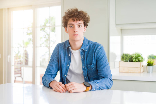 Young handsome man wearing casual denim jacket at home Relaxed with serious expression on face. Simple and natural looking at the camera. - Foto, Imagem