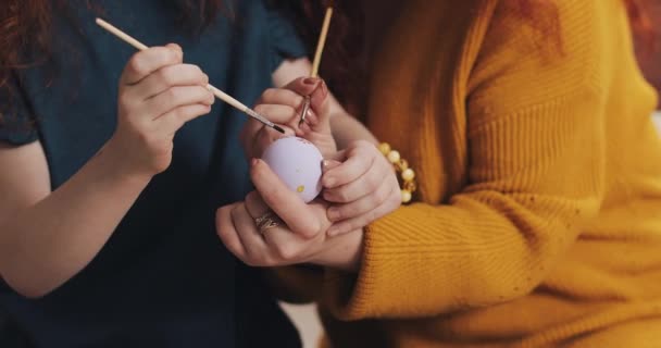 Close up of mother and daughter hands coloring easter eggs with colors and brush. Colorful easter eggs. Preparation of the Easter - Кадры, видео