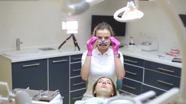 歯医者さん。歯医者への診察と歯のクリーニングのための患者の肖像画。歯医者は鏡で若い女性の歯をチェックする。歯列矯正手術後の笑顔の女性の肖像画 - 映像、動画