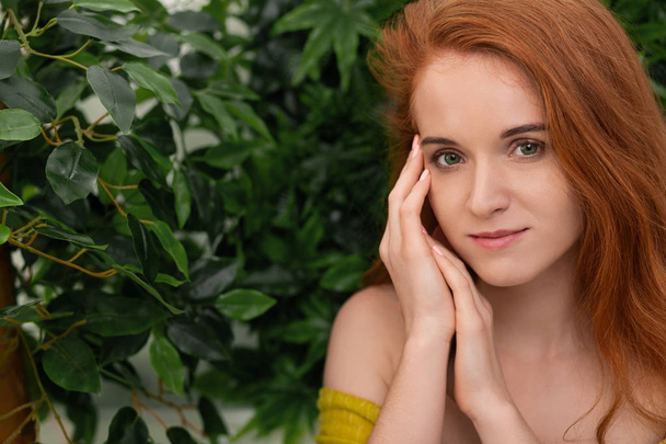 彼女の顔、緑の背景に触れる若い赤毛の女性 - 写真・画像