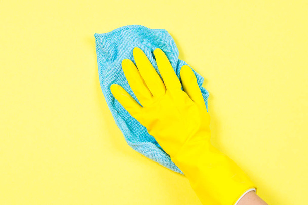 黄色の手袋と黄色の背景を洗浄マイクロファイバー雑巾で手します。. - 写真・画像