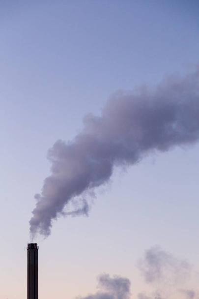 Lämpölaitoksen savupiipusta tuleva savu kylmänä talvi-iltana
 - Valokuva, kuva