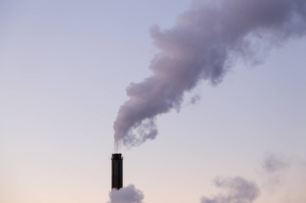 Lämpölaitoksen savupiipusta tuleva savu kylmänä talvi-iltana
 - Valokuva, kuva