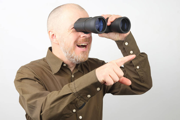 Hombre barbudo con prismáticos en sus manos mirando felizmente hacia el
 - Foto, Imagen