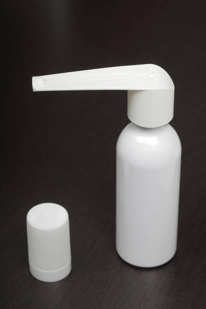 Inhaler for the treatment of respiratory organs. Spray can and cap white. On a dark surface. - Фото, изображение