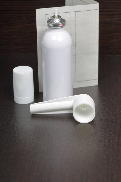 Inhaler for the treatment of respiratory organs. Spray can and cap white. Next recipe to buy. On a dark surface. - Фото, изображение
