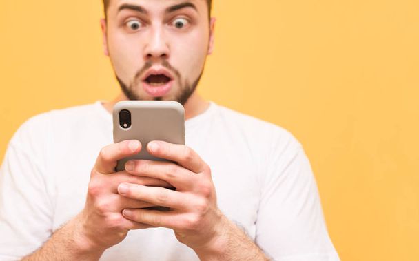 Close-up photo, shocked man looking at a smartphone. Amazed man  - Foto, immagini