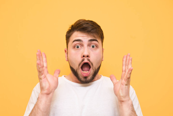 Close portrait of a surprised man on a yellow background looks a - Foto, Imagem