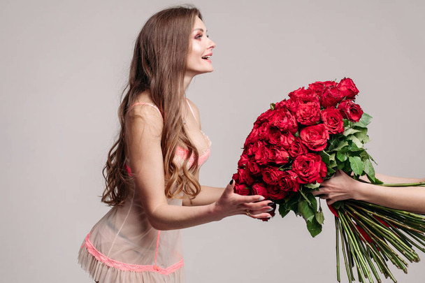 Μερική άποψη του ενθουσιασμένος γυναίκα να πάρει μεγάλο μπουκέτο από κόκκινα τριαντάφυλλα - Φωτογραφία, εικόνα
