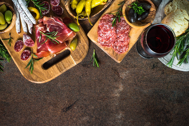 Antipasto - carne fatiada, presunto, salame, azeitonas na vista superior da mesa de pedra escura
. - Foto, Imagem
