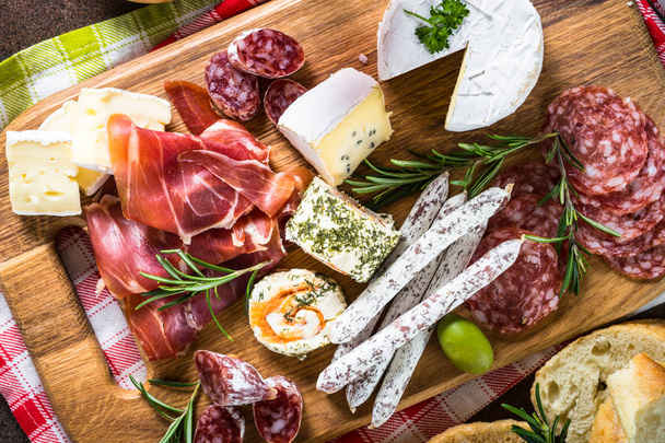 Antipasto delicatessen - gesneden vlees, ham, salami, olijven op houten plank.  - Foto, afbeelding