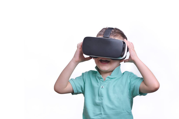 Amazed teen boy wearing virtual reality goggles watching movies or playing video games, isolated on white. Surprised teenager looking in VR glasses. Emotional portrait of child experiencing 3D gadget - Photo, image