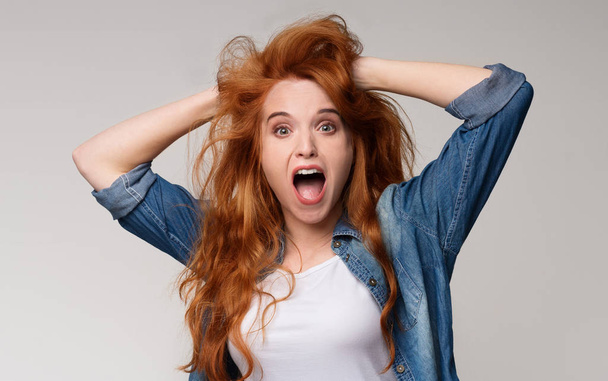 Amazed redhead woman clutched her head in surprise - Photo, Image