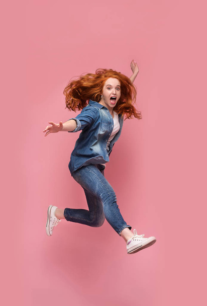 Lachende jonge roodharige vrouw springen in de lucht - Foto, afbeelding