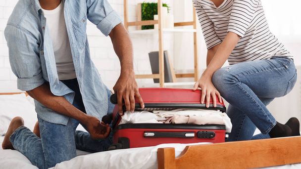 Packing suitcase. Couple trying to close valise - Photo, Image