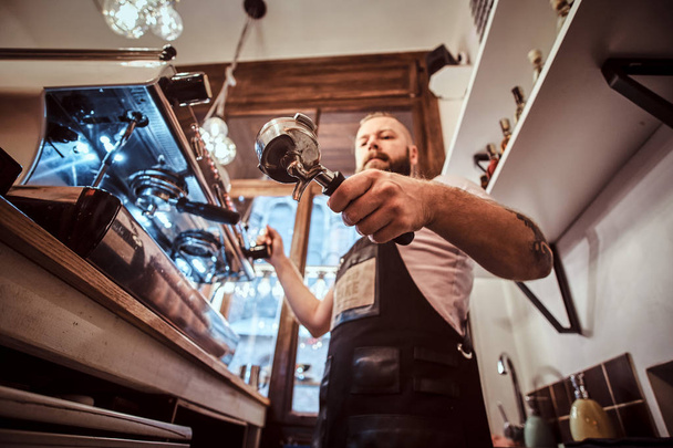 Low angle photo of a barista holding a portafilter, working in the coffee shop - Photo, Image