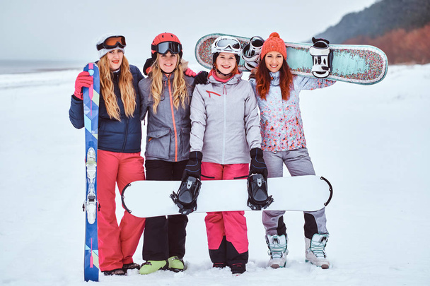Iloinen naiset ystäviä urheilu talvivaatteita lumilaudat ja sukset poseeraa
  - Valokuva, kuva