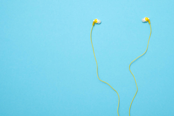 Yellow headphones on blue background. Modern accessory for listening to music. - Foto, Imagem