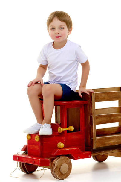 Little boy is playing with a wooden car. - Φωτογραφία, εικόνα