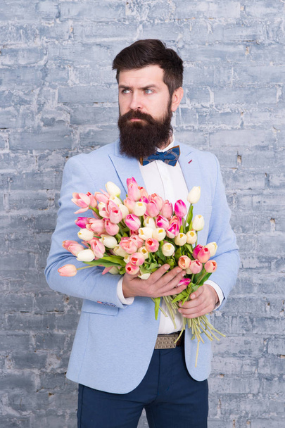 We take flowers personally. Spring gift. Bearded man hipster with flowers. Love. international holiday. Womens day. March 8. Bearded man with tulip spring bouquet. Spring time. enjoying spring - Photo, image