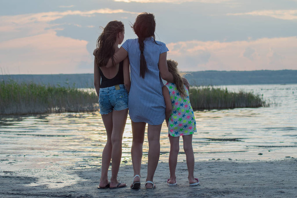 ritratto di una giovane madre e dei suoi figli, si abbracciano al tramonto - Foto, immagini