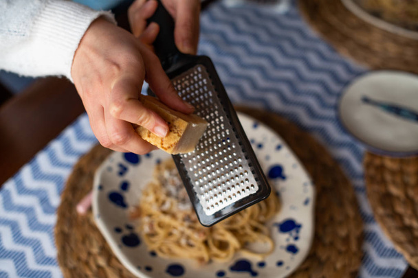 woman hands grating parmesan cheese on pasta carbonara - Photo, Image
