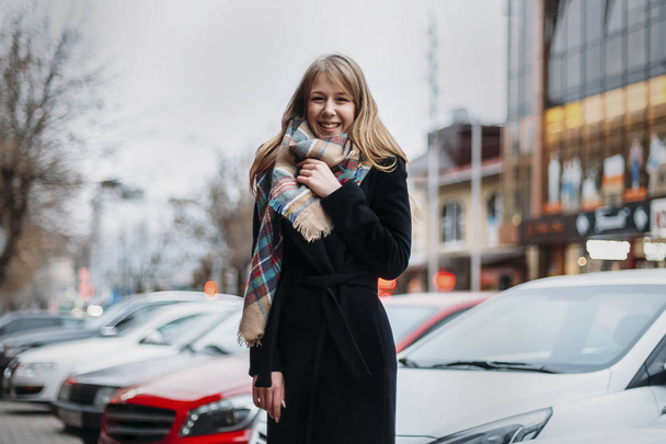 young happy woman in coat and scarf laughing. girl walking aroun - Fotó, kép