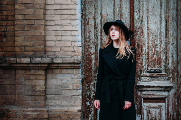 Blonde girl with long hair, in black coat in hat, stands on the  - Foto, Imagem