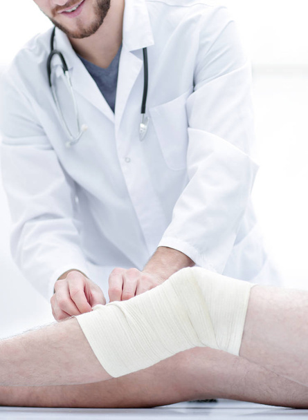 Arzt untersucht Verband am Bein des Patienten - Foto, Bild